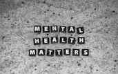 Black tiles with white letters spell out 'MENTAL HEALTH MATTERS' on a textured gray stone surface.