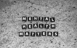 Black tiles with white letters spell out 'MENTAL HEALTH MATTERS' on a textured gray stone surface.