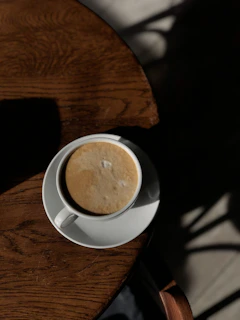 A sleek stainless steel travel cup resting on a wooden table with morning sunlight.