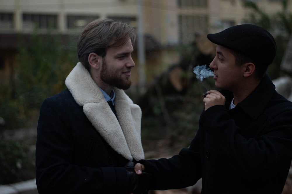 man in black coat holding white flower