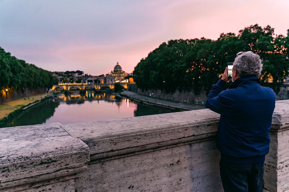 man in black jacket taking photo of river during daytime