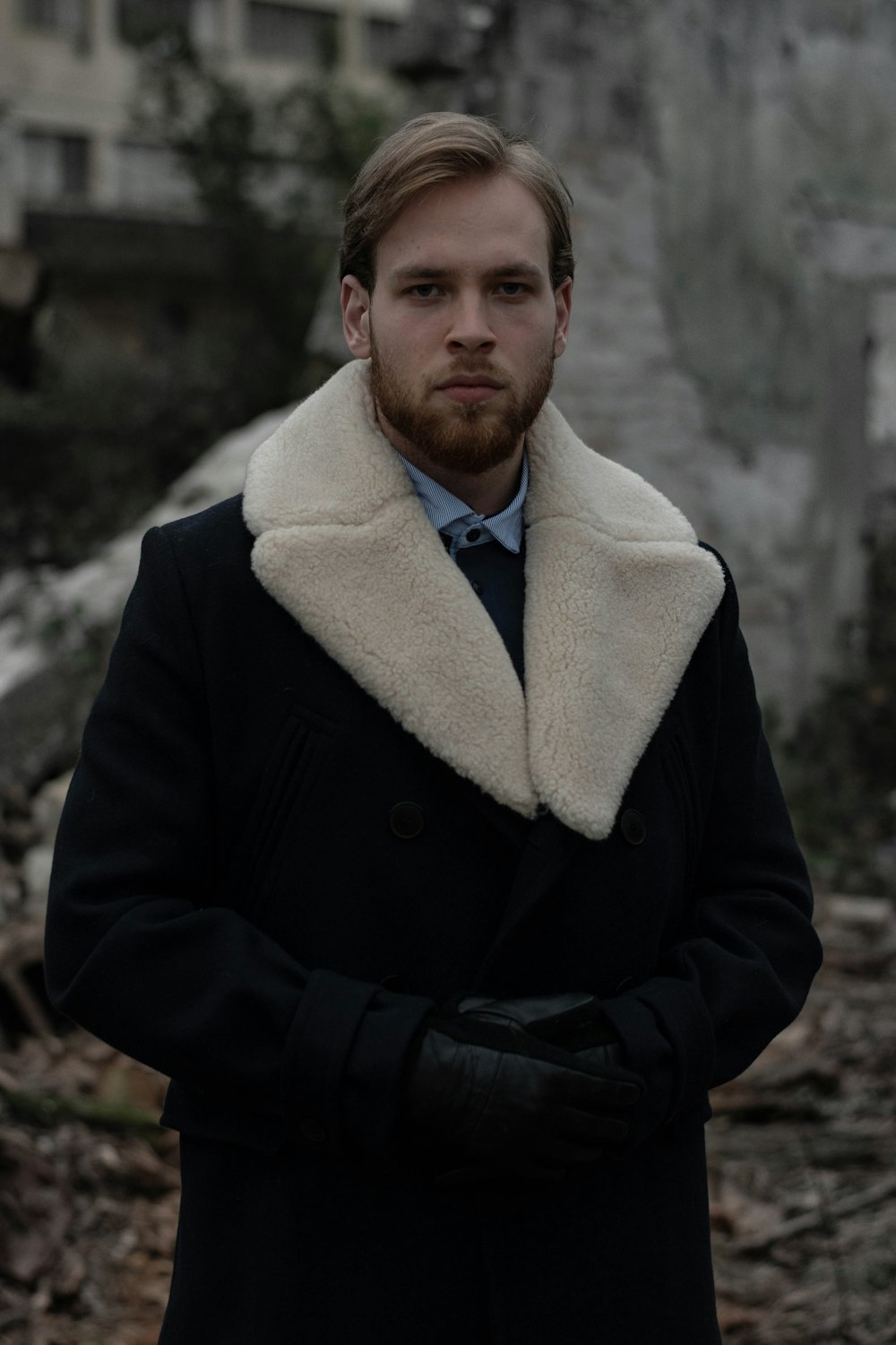 man in black coat standing near gray wall