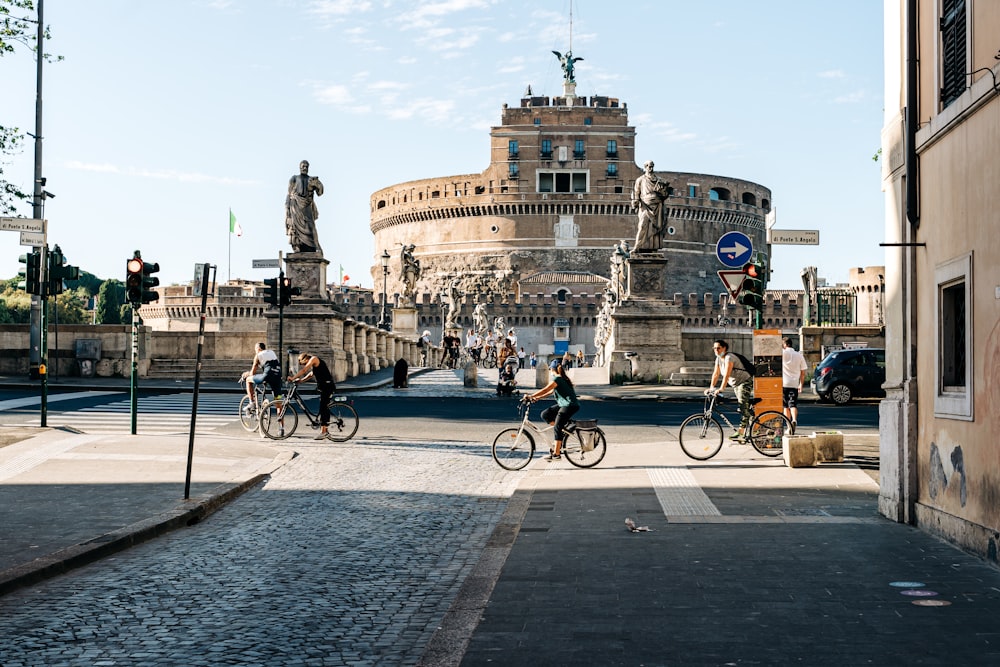 people riding bicycle on road near concrete building during daytime