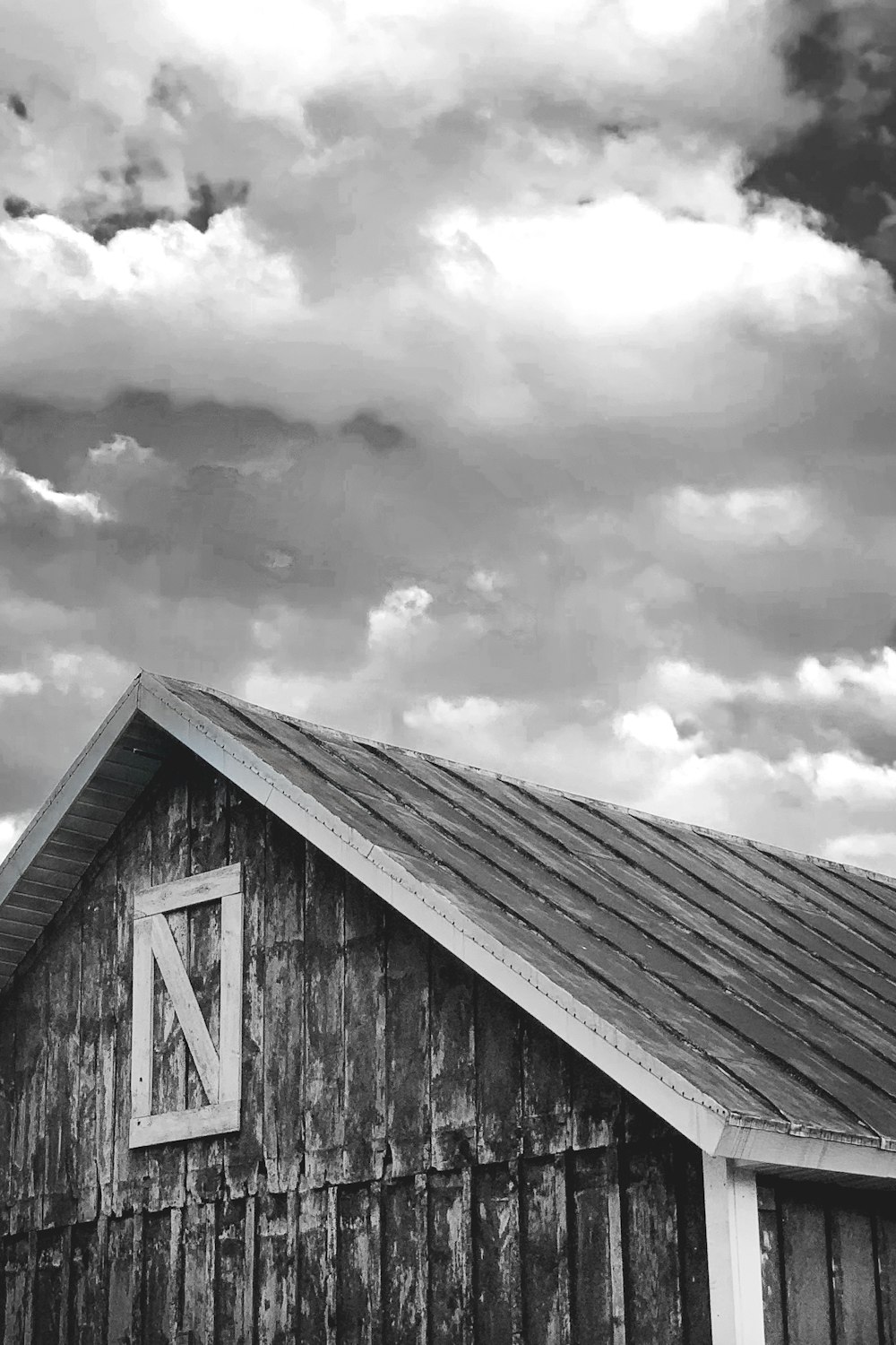 grayscale photo of wooden house under cloudy sky