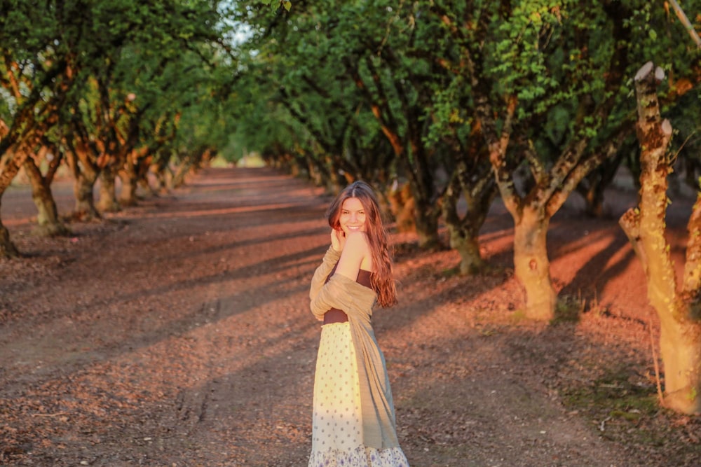 woman in white and brown dress standing on road during daytime