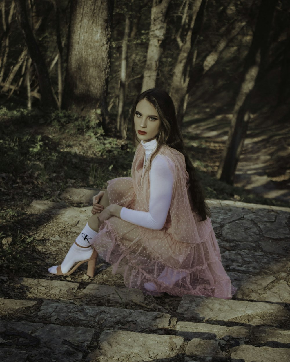 girl in pink dress sitting on brown rock