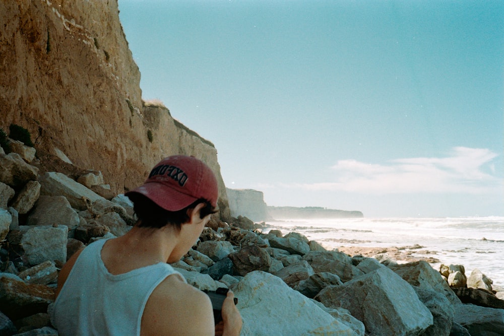 uma pessoa sentada em rochas perto do oceano