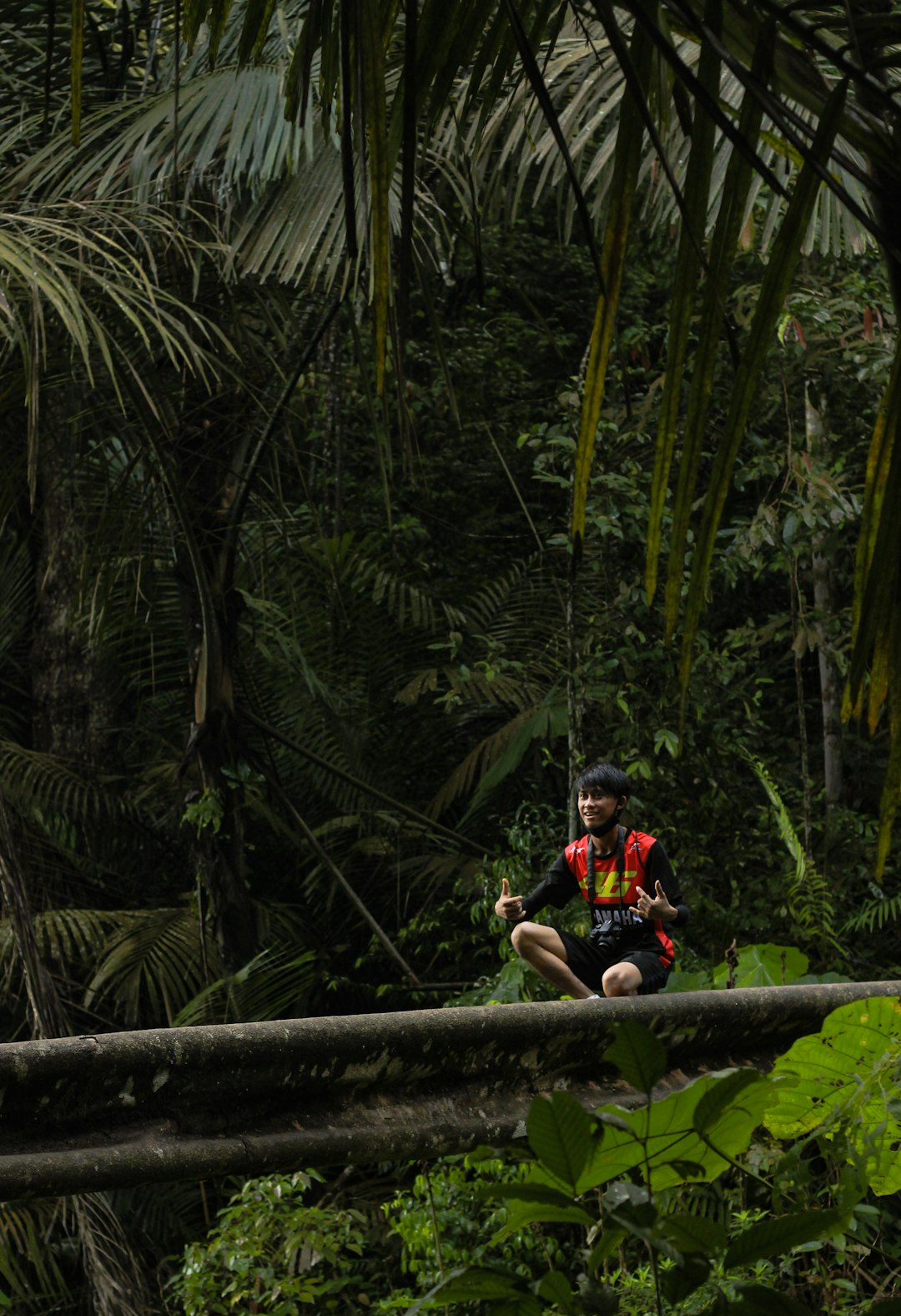 man in black and red jacket and blue helmet sitting on brown wooden bridge