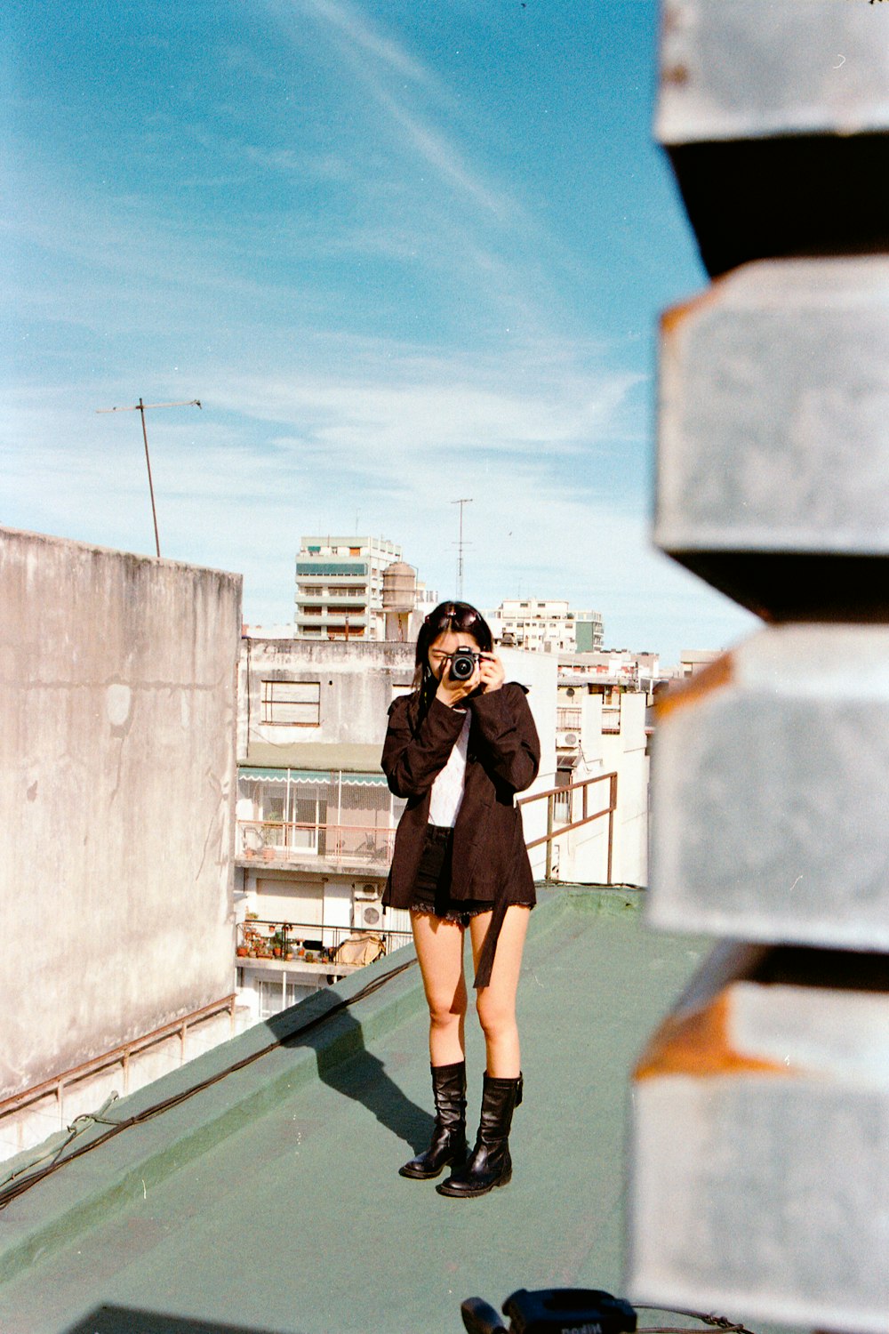a woman taking a picture of herself on a rooftop