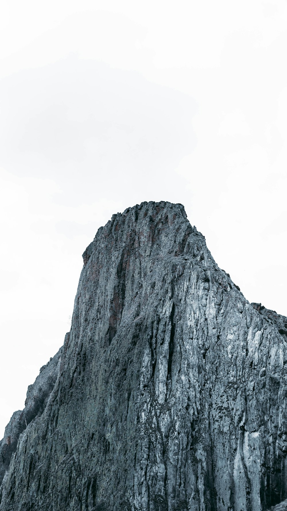 montanha rochosa cinzenta sob o céu branco durante o dia