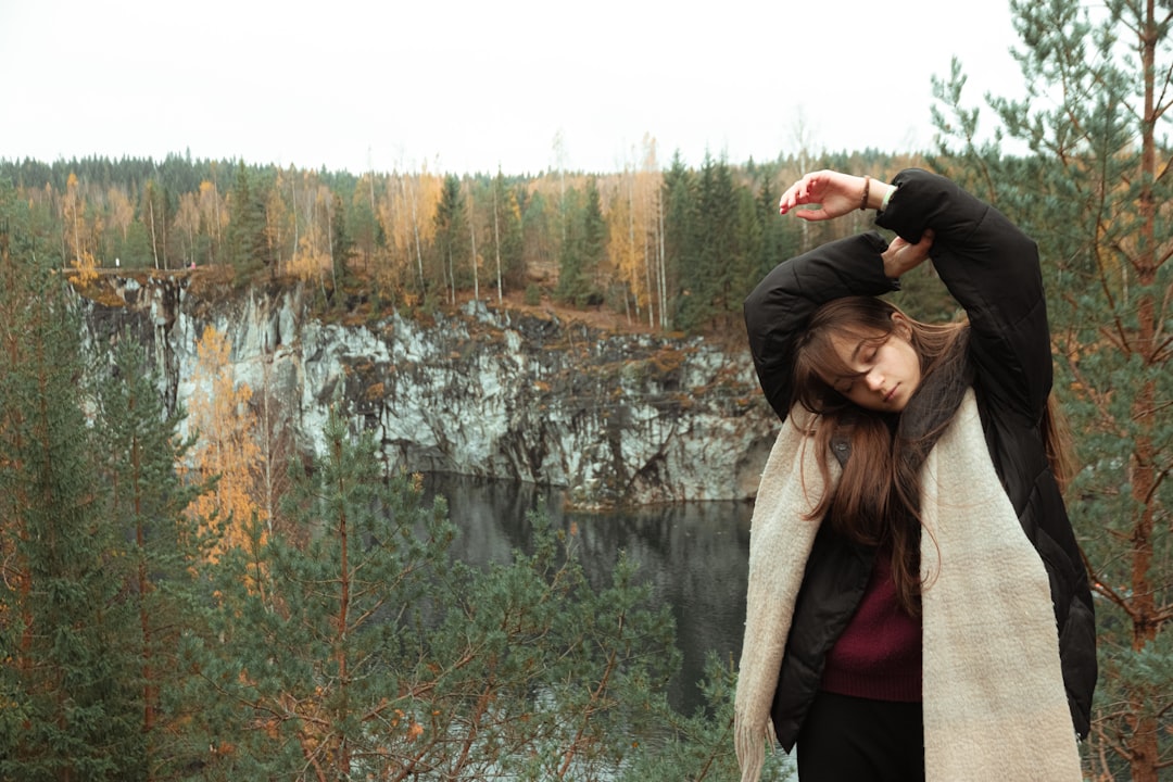 woman in black jacket standing near lake during daytime