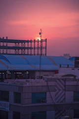 Technician installing telecom cables on a modern building rooftop at sunset.