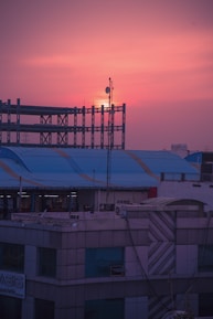 Architects reviewing blueprints on a rooftop overlooking a developing city skyline at sunset.