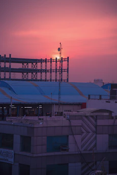 Technician installing telecom cables on a modern building rooftop at sunset.