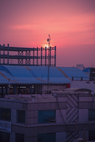 Architects reviewing blueprints on a rooftop overlooking a developing city skyline at sunset.