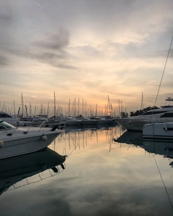 Calm marina at sunset with yachts docked along the pier under soft blue sky