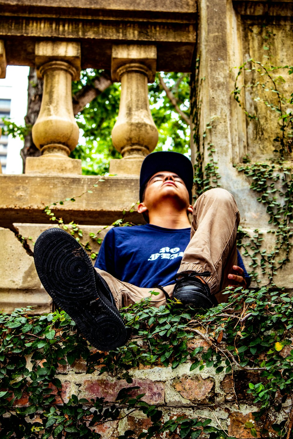 man in blue crew neck t-shirt and brown pants sitting on brown concrete bench during