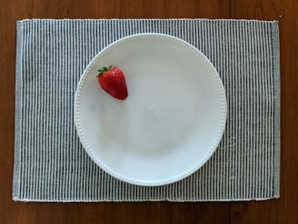 red strawberry on white ceramic plate