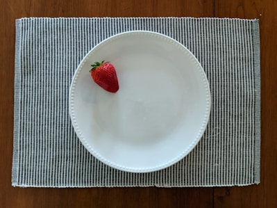 red strawberry on white ceramic plate
