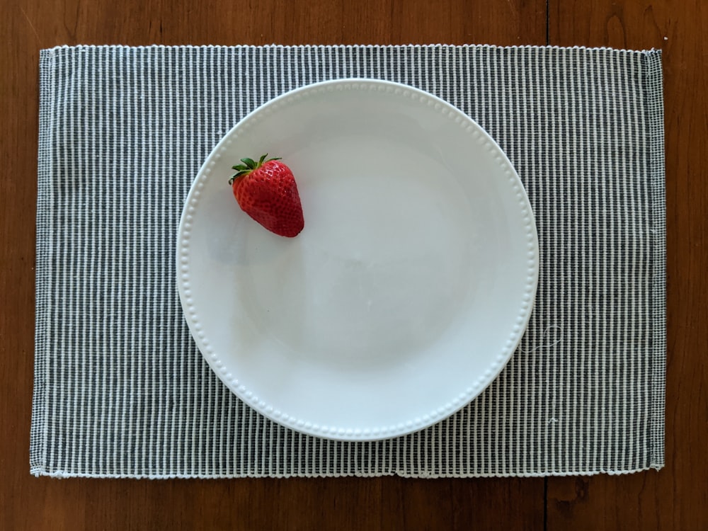 red strawberry on white ceramic plate