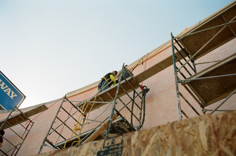 Un homme en chemise jaune grimpe sur un bâtiment en béton brun pendant la journée