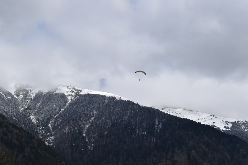 person riding parachute over snow covered mountain during daytime