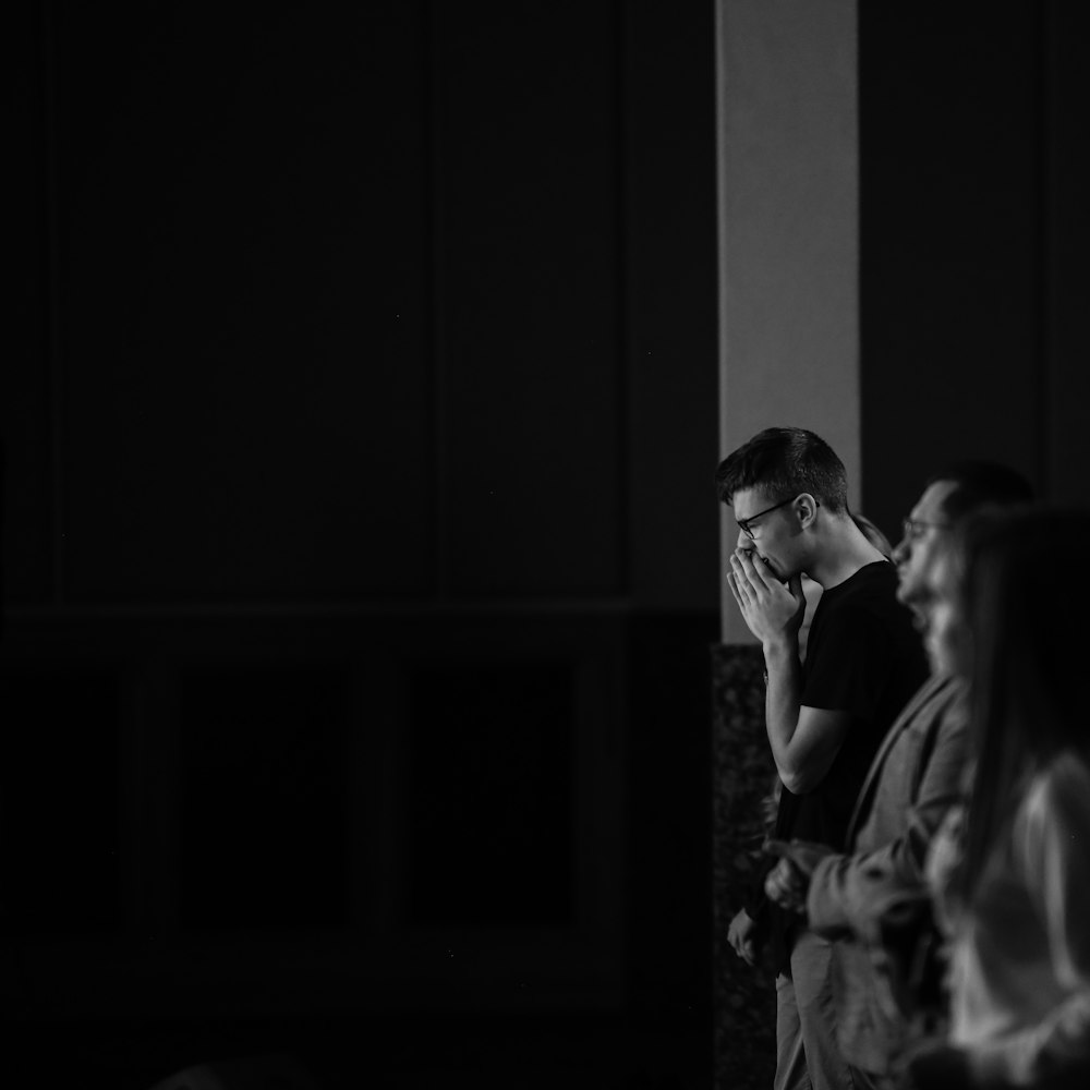 grayscale photo of man and woman standing near window