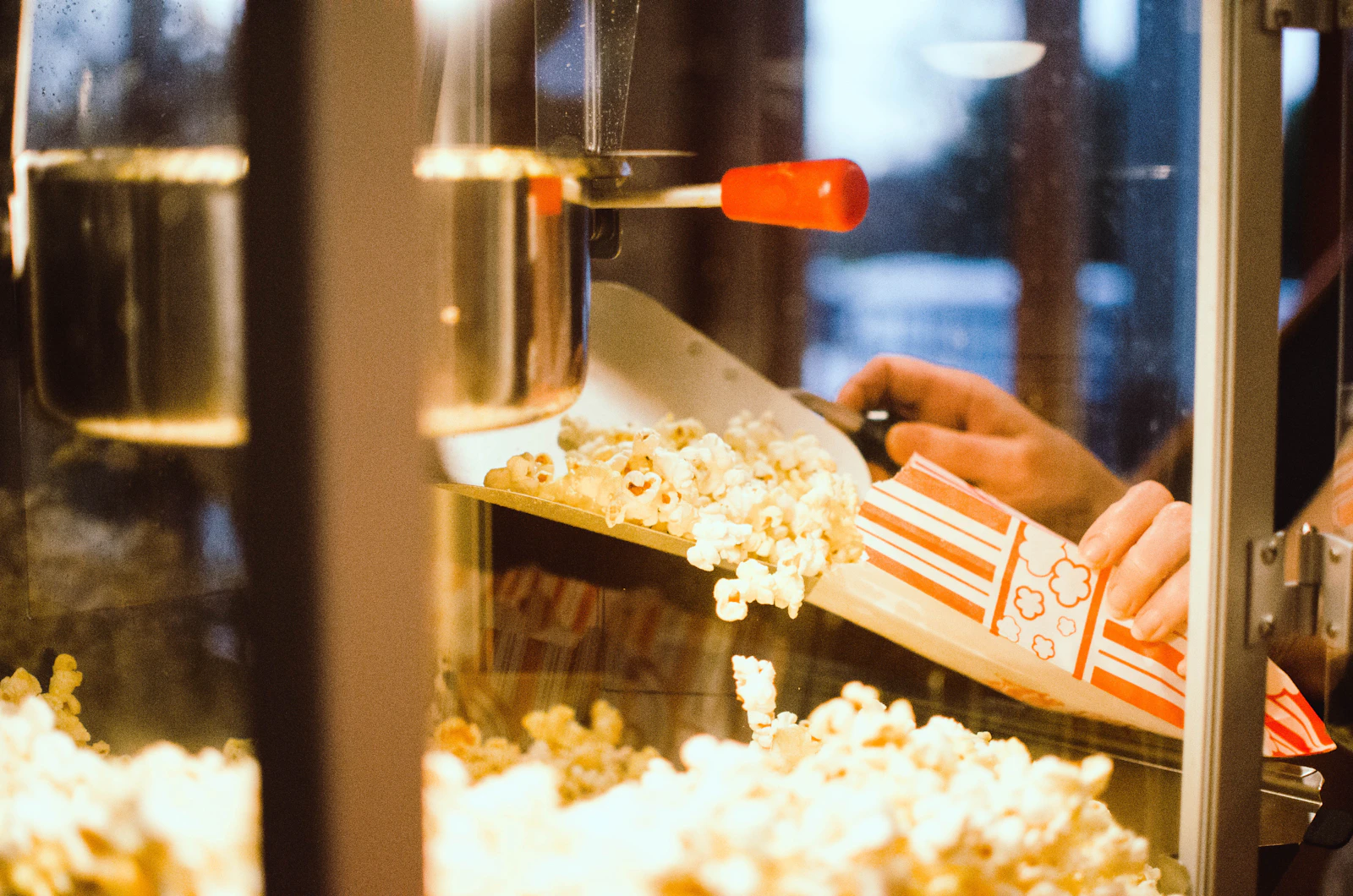Hands holding a striped popcorn tub