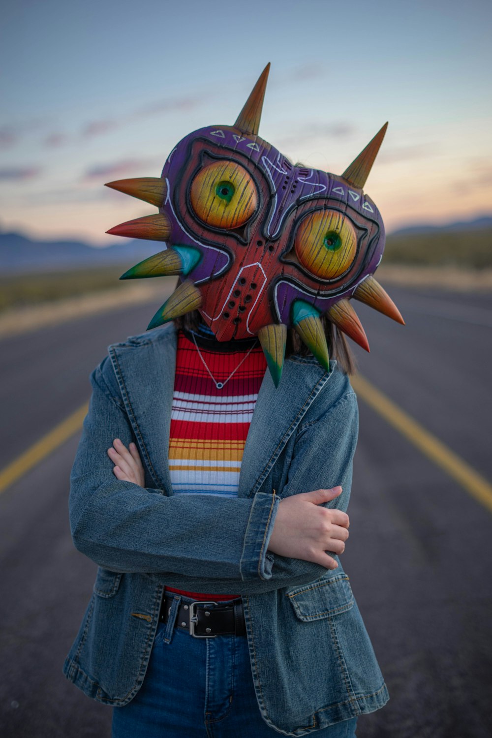 person in blue denim jacket with yellow green and blue owl mask