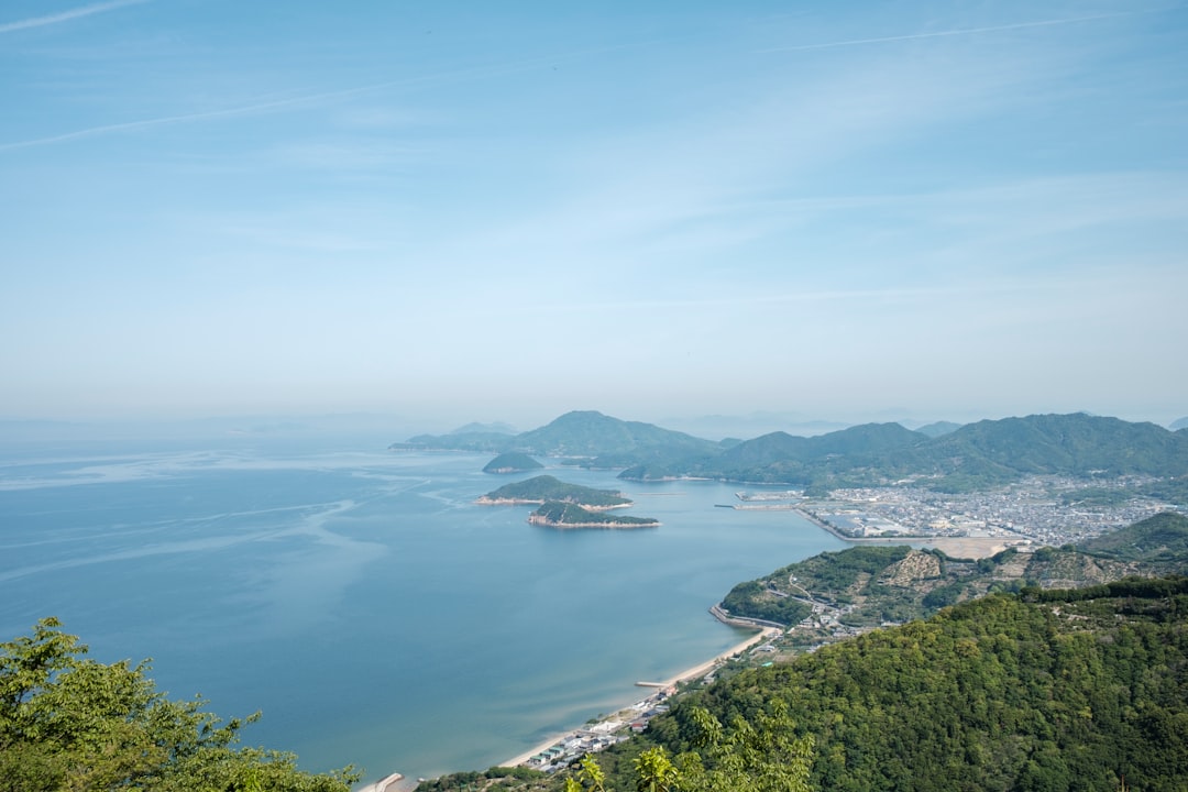 green mountain beside body of water during daytime