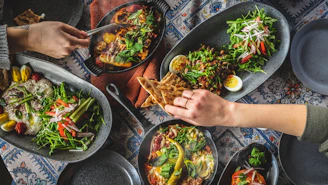 person holding vegetable salad on black ceramic plate
