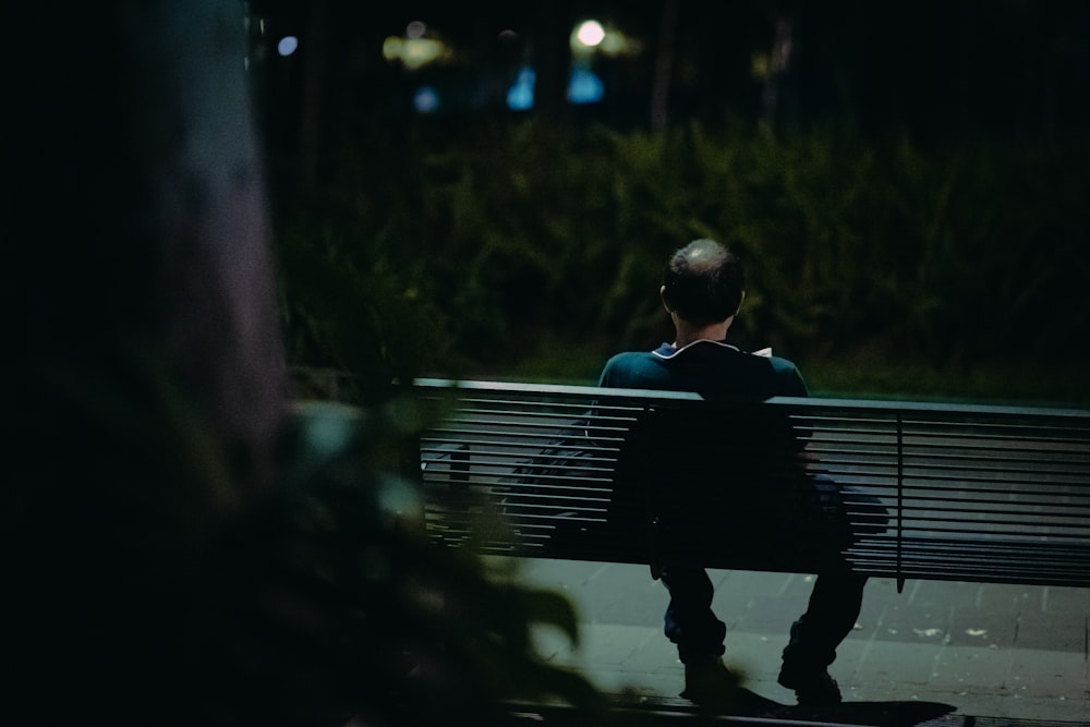 man in black shirt sitting on bench