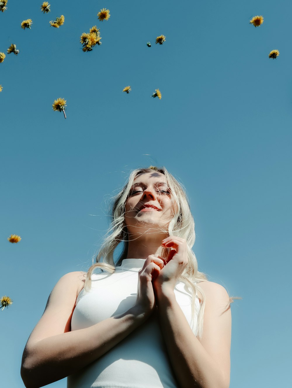woman in white tank top holding yellow flowers