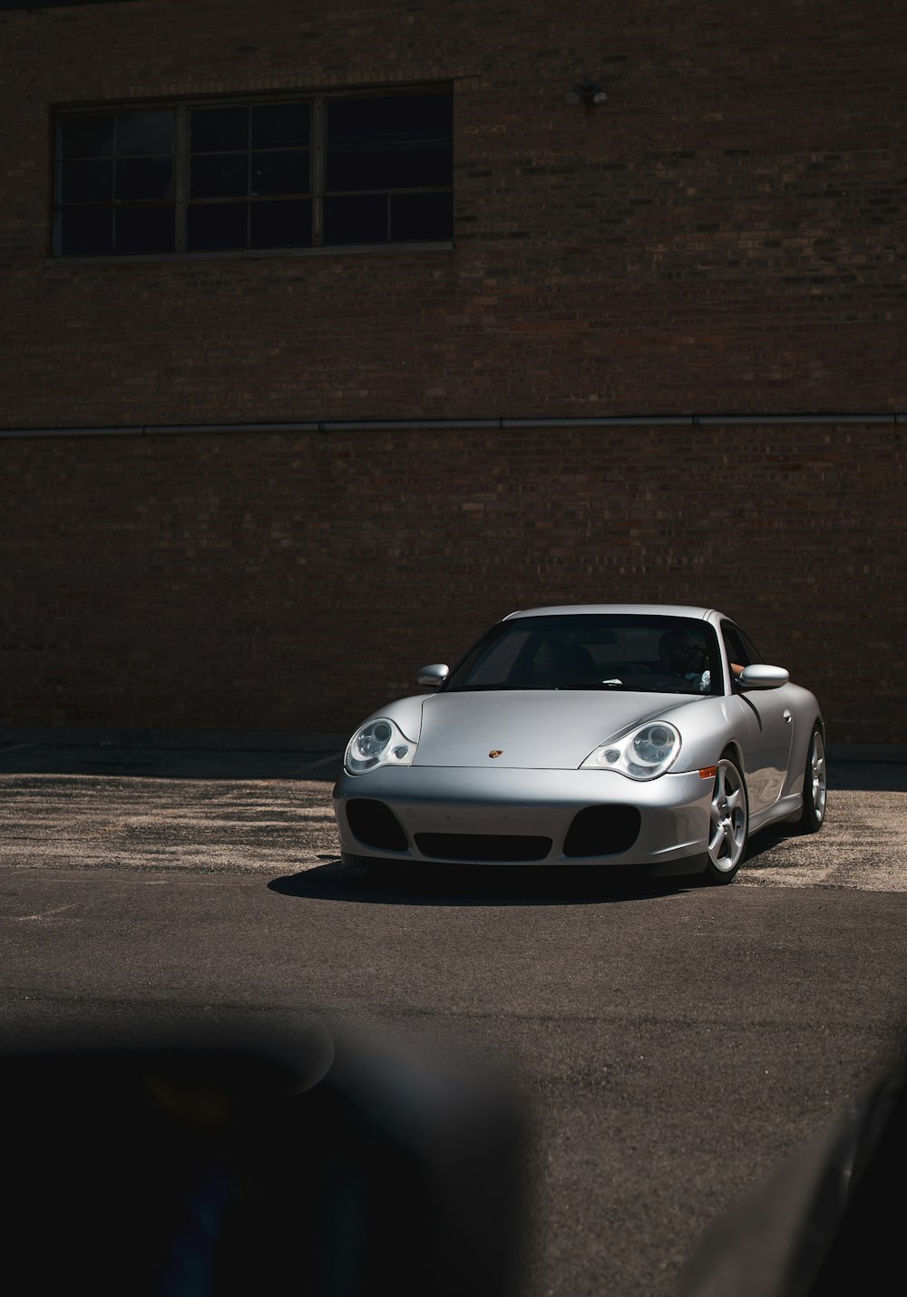 silver porsche 911 parked beside brown brick wall