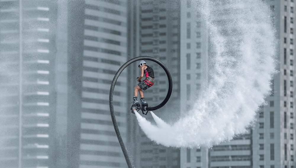 man in orange jacket riding bicycle on white water wave during daytime