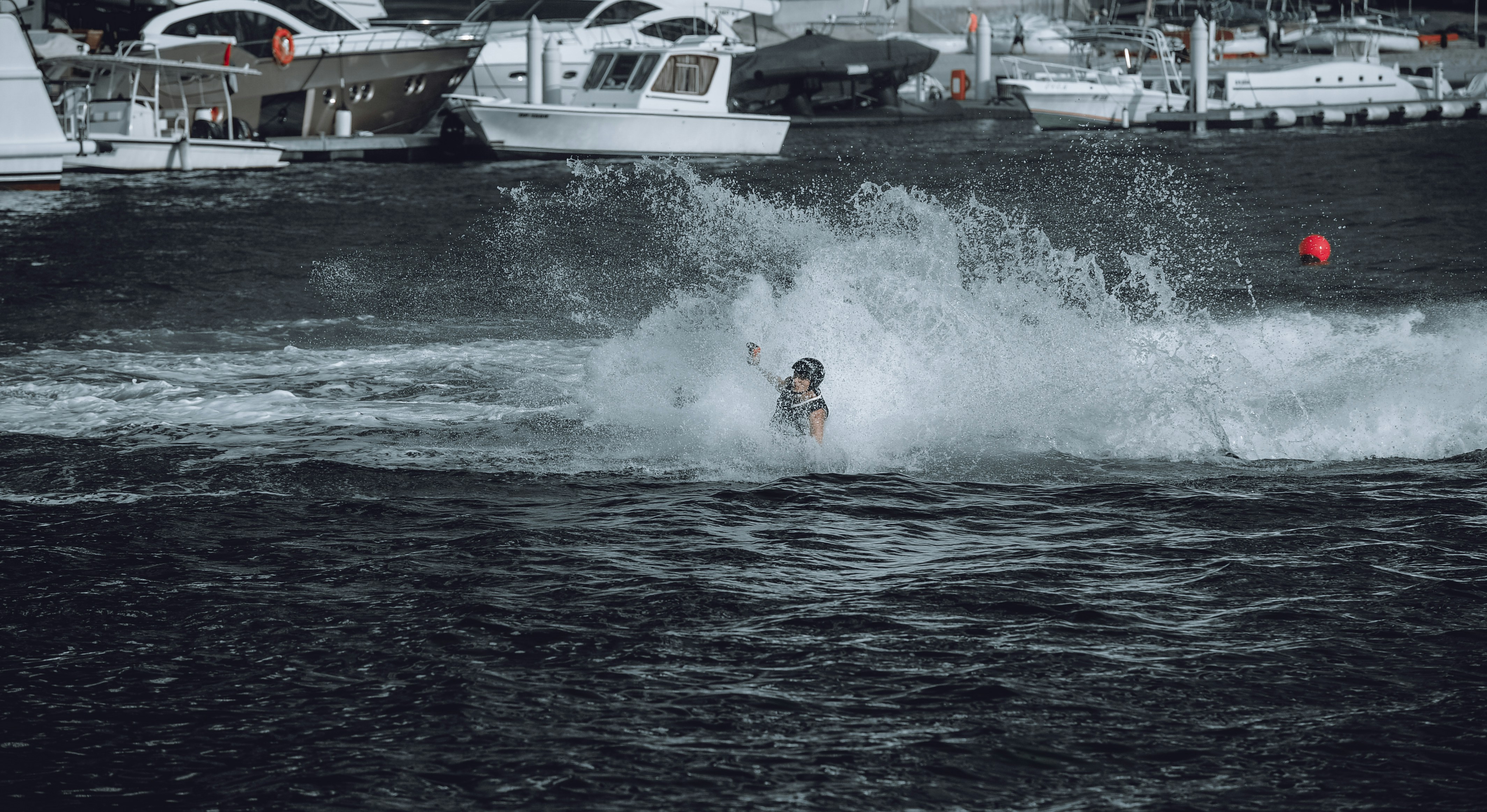 A man riding a wave on top of a surfboard photo Free Dubai marina