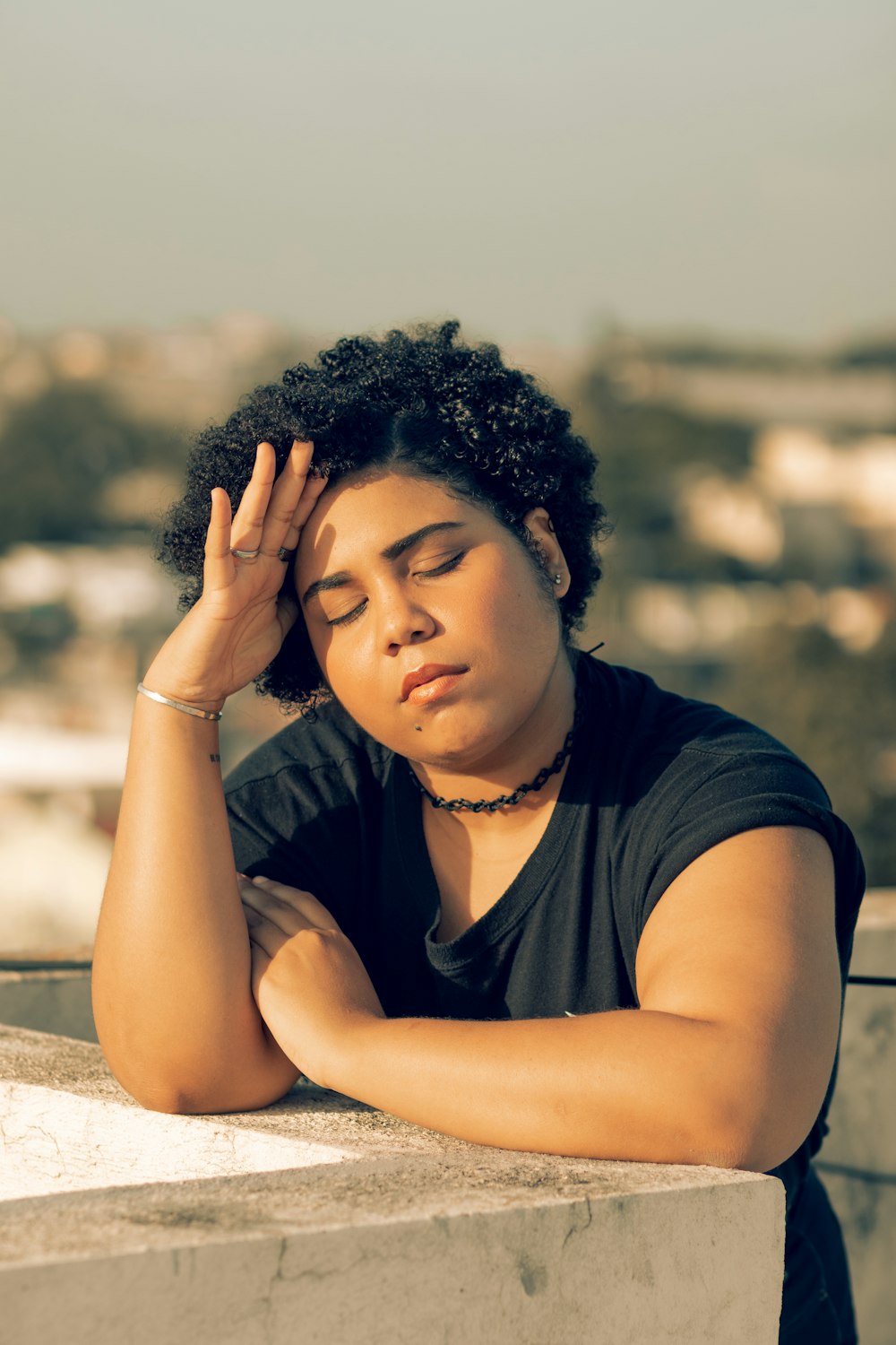 a woman sitting on a ledge with her hands on her head