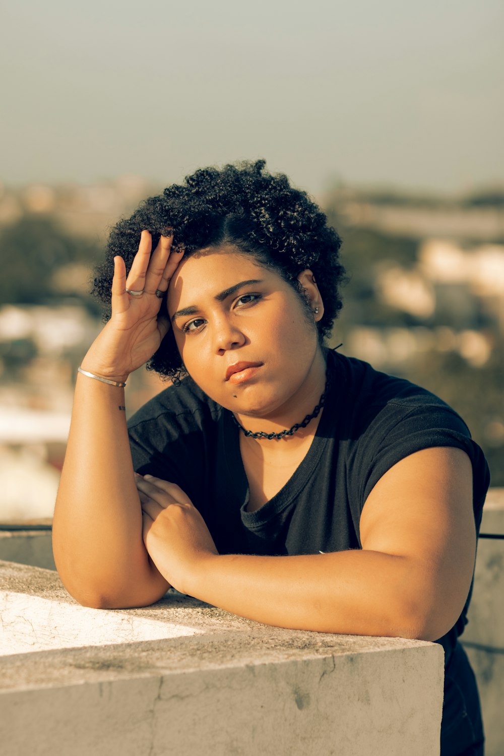 a woman leaning on a ledge with her hand on her head