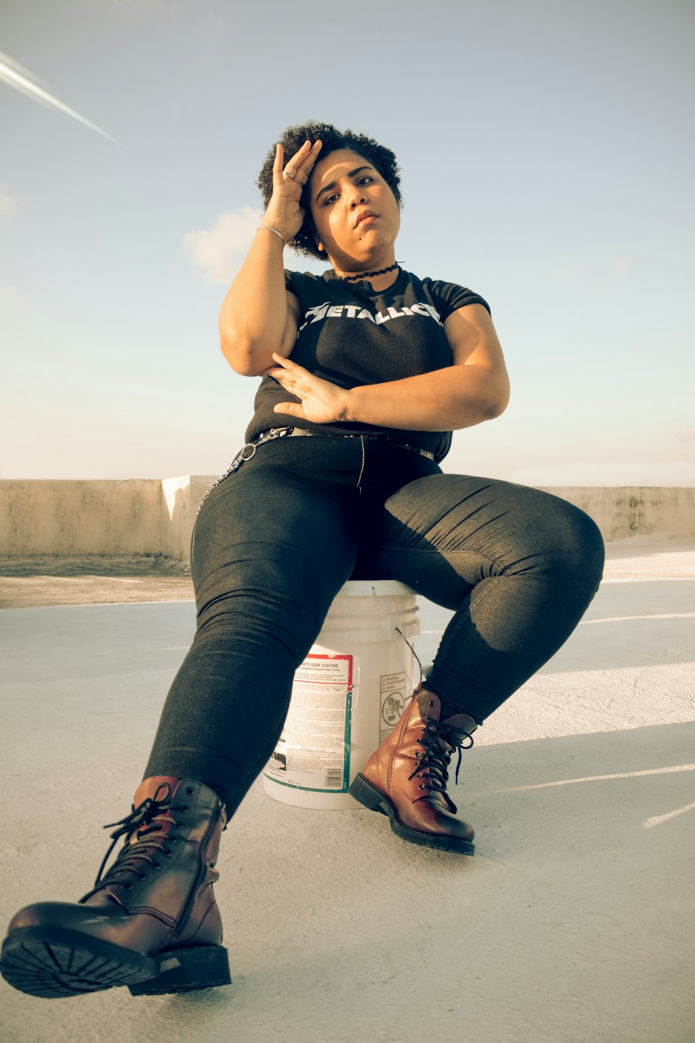 woman in black tank top and blue denim jeans sitting on gray concrete floor during daytime