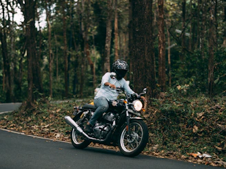 man in white shirt riding black motorcycle on road during daytime