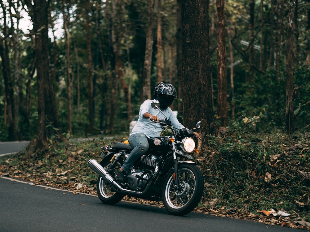 Hombre con camisa blanca conduciendo una motocicleta negra en la carretera durante el día