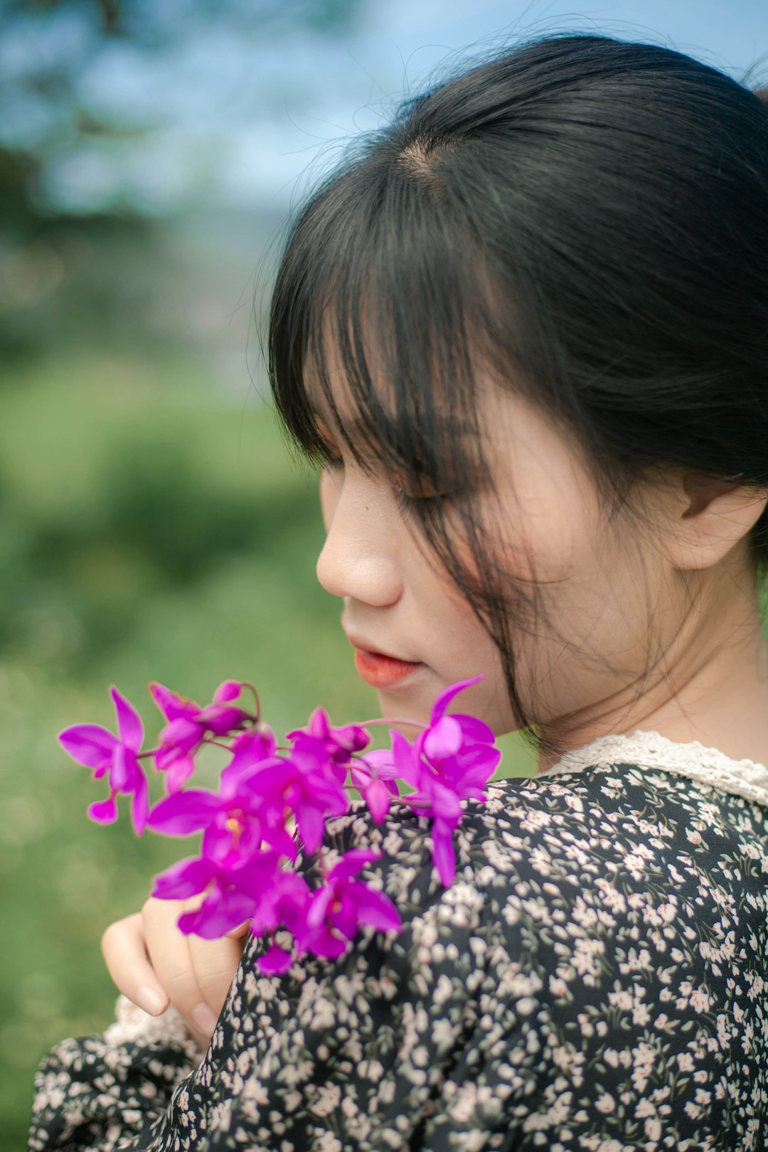 woman in black and white floral shirt holding purple flower