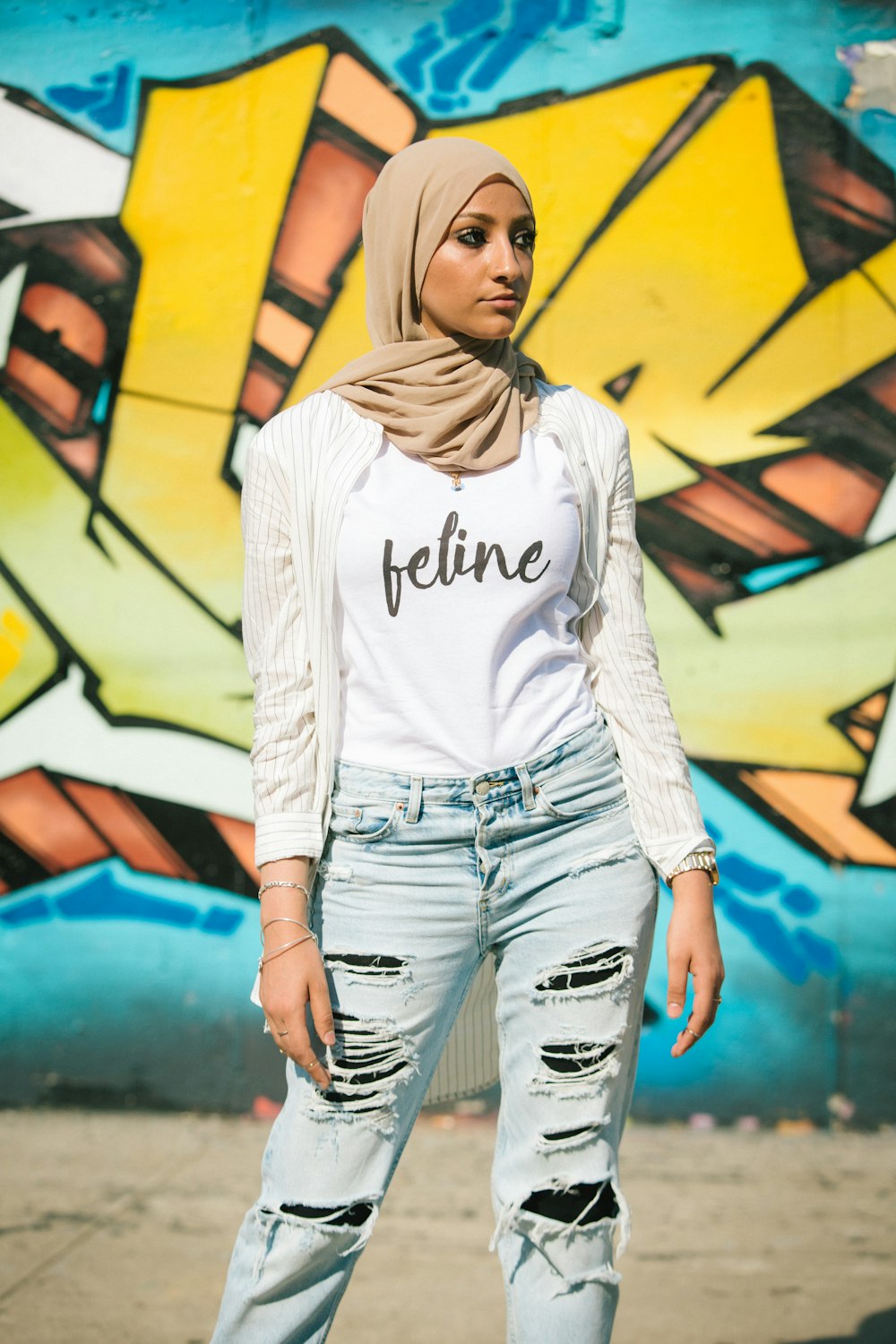 woman in white long sleeve shirt and blue denim shorts standing beside yellow and black wall