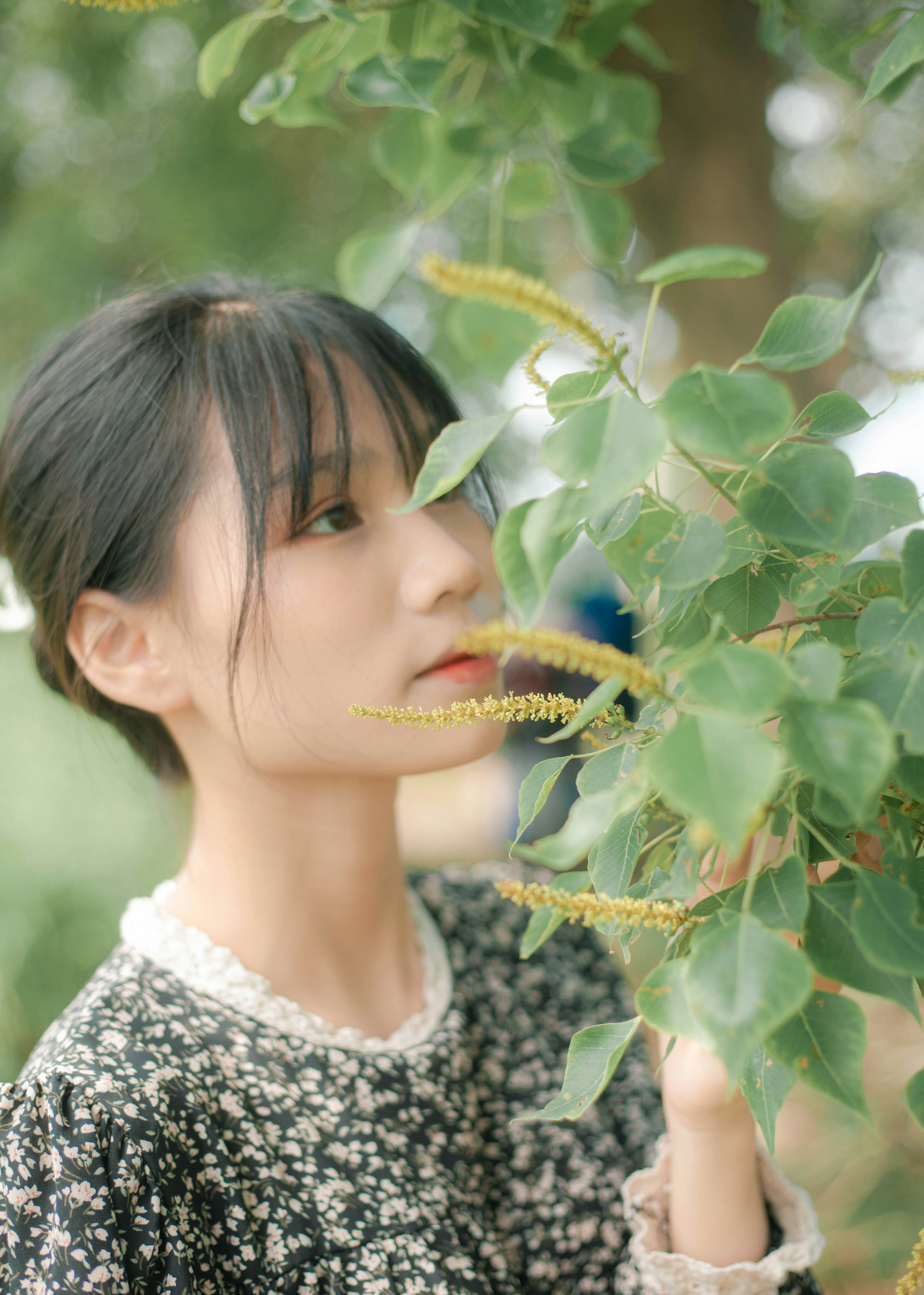 menina na camisa floral branca e preta que está ao lado da planta verde durante o dia