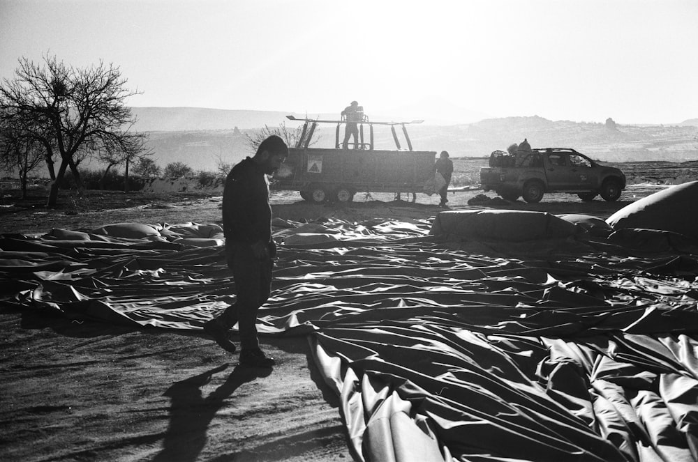 man in black jacket and pants standing on boat in grayscale photography