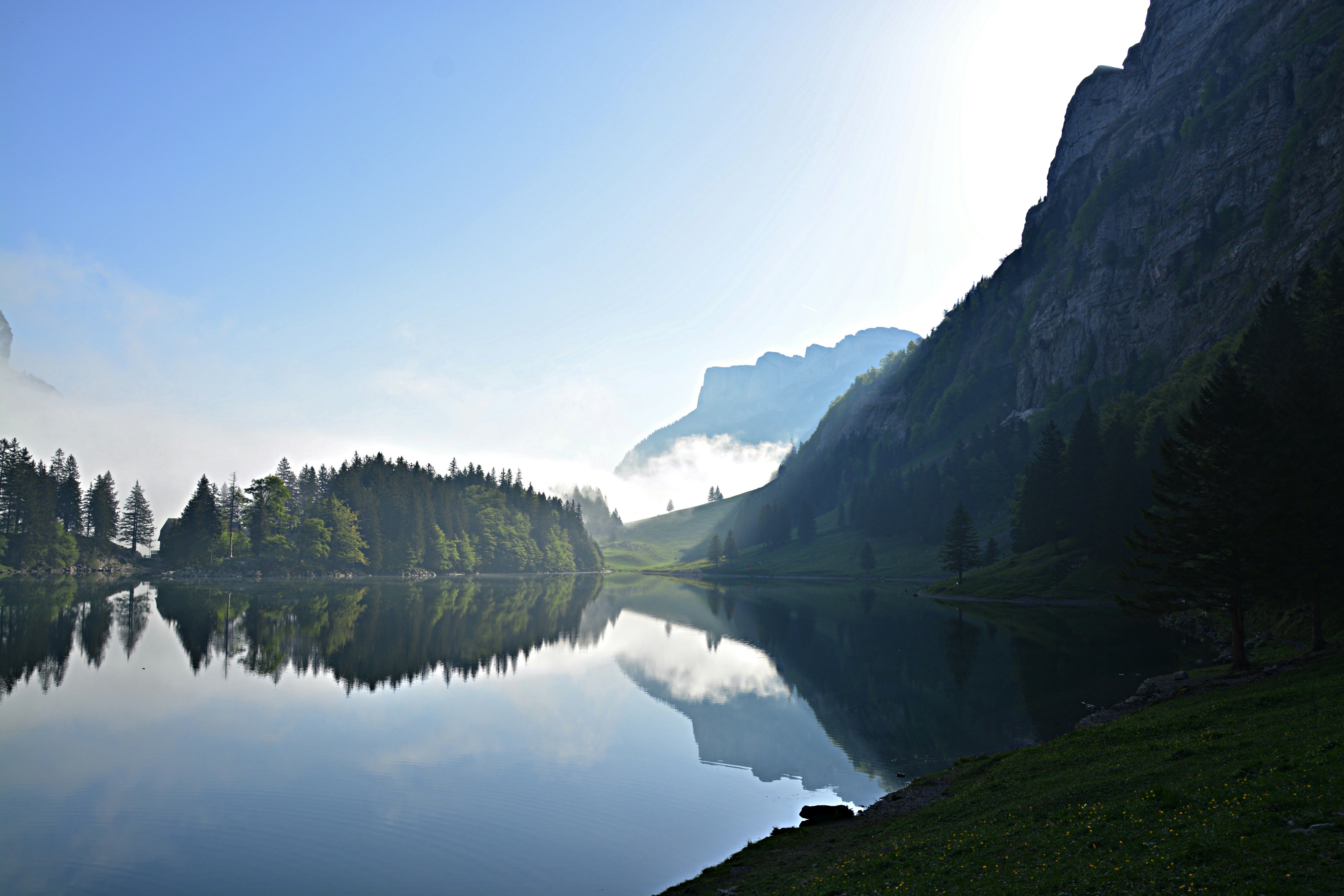 lake surrounded by green trees and mountains during daytime, Early morning hike in Switzerland.