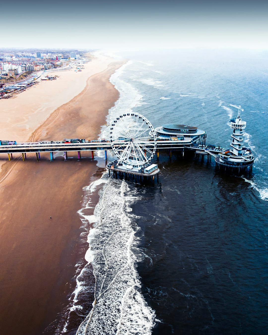 white ferris wheel on brown sand near body of water during daytime