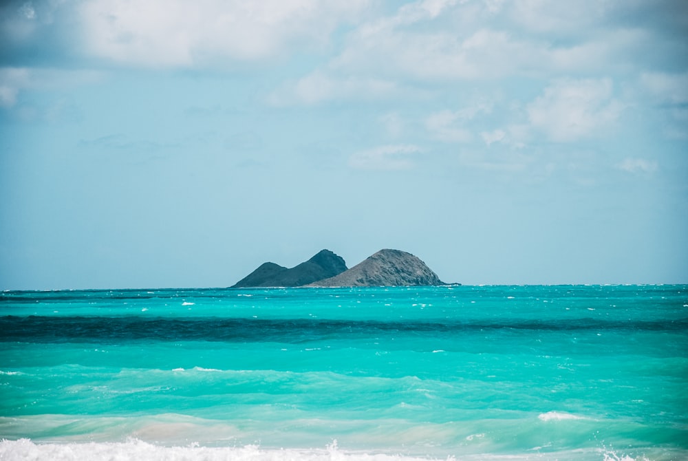 green and brown mountain beside body of water under white clouds during daytime