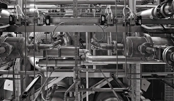 A complex network of industrial metal pipes and valves in a factory setting