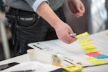 Close-up of hands organizing sticky notes on a project planning board.